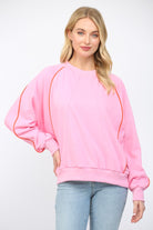 Woman wearing a pink sweatshirt with orange accents on a white background