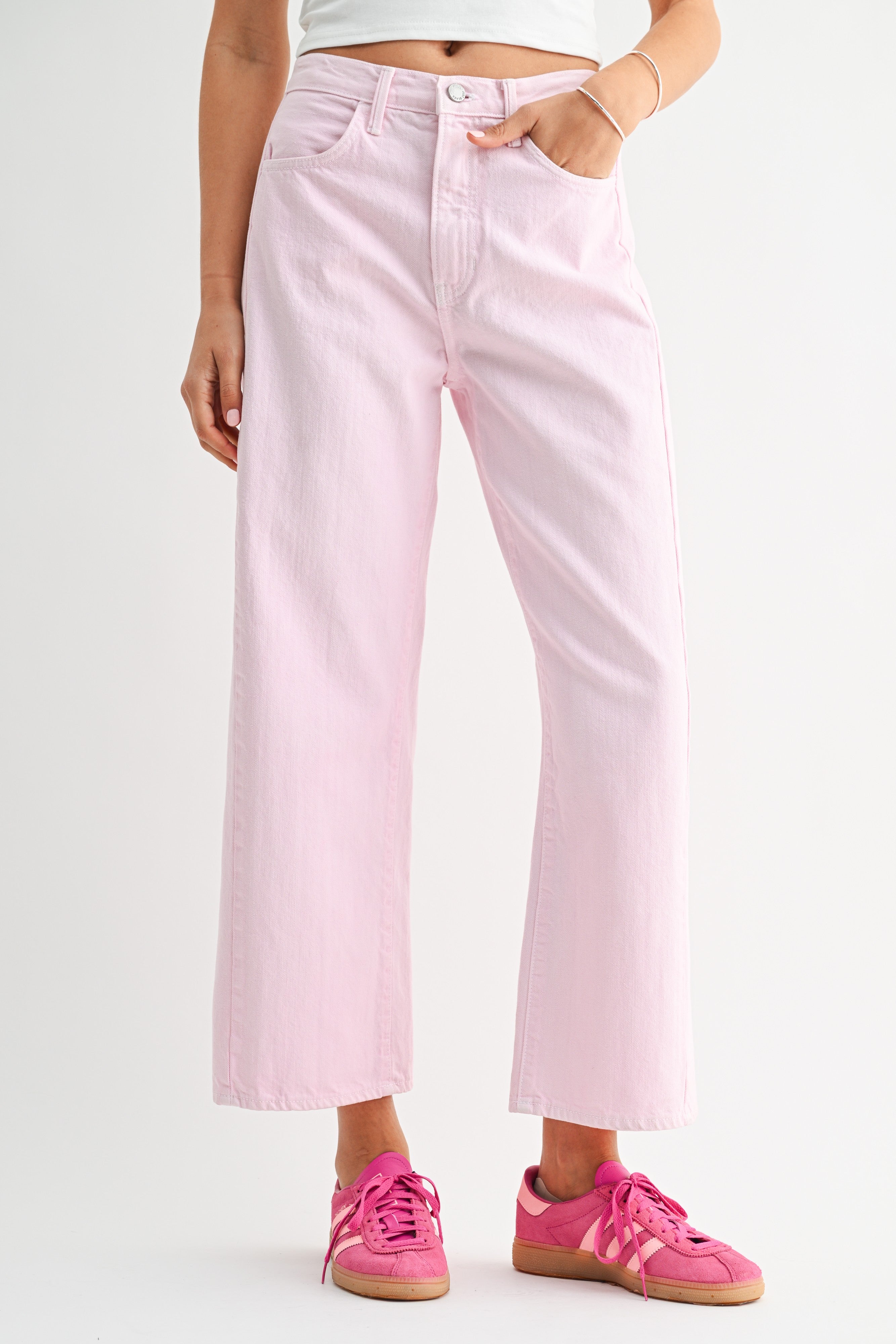 Person wearing light pink jeans and pink sneakers on a white background