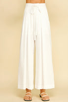 White wide-leg pants worn by a person on a beige background
