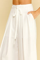 White wide-leg pants with a tie waist on a beige background