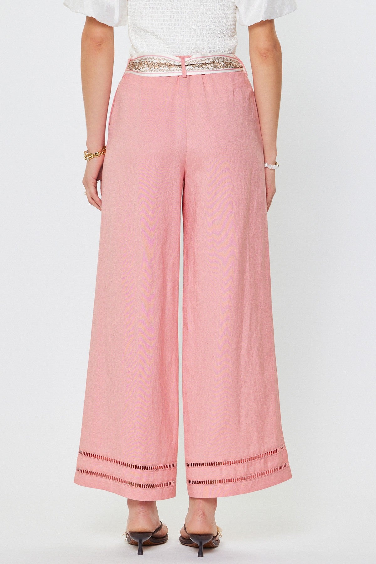 Pink pants with decorative trim worn by a person on a white background