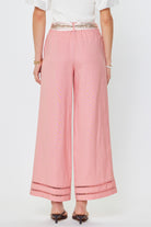 Pink pants with decorative trim worn by a person on a white background