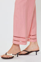 Person wearing pink pants with lace details and black high-heeled sandals on a white background