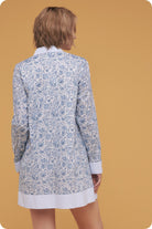 Woman wearing a blue floral patterned cardigan on a mustard yellow background