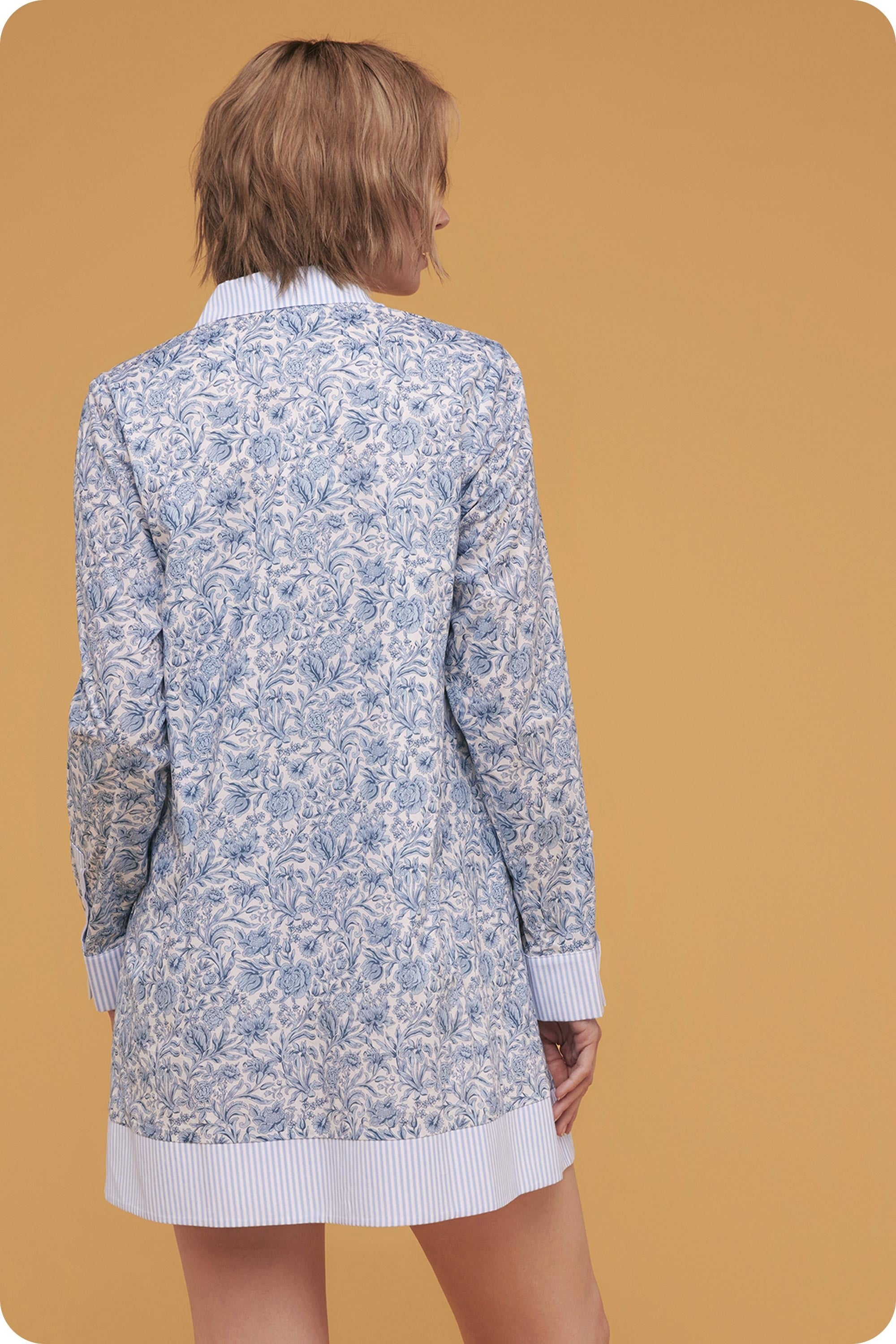 Woman wearing a blue floral patterned cardigan on a mustard yellow background