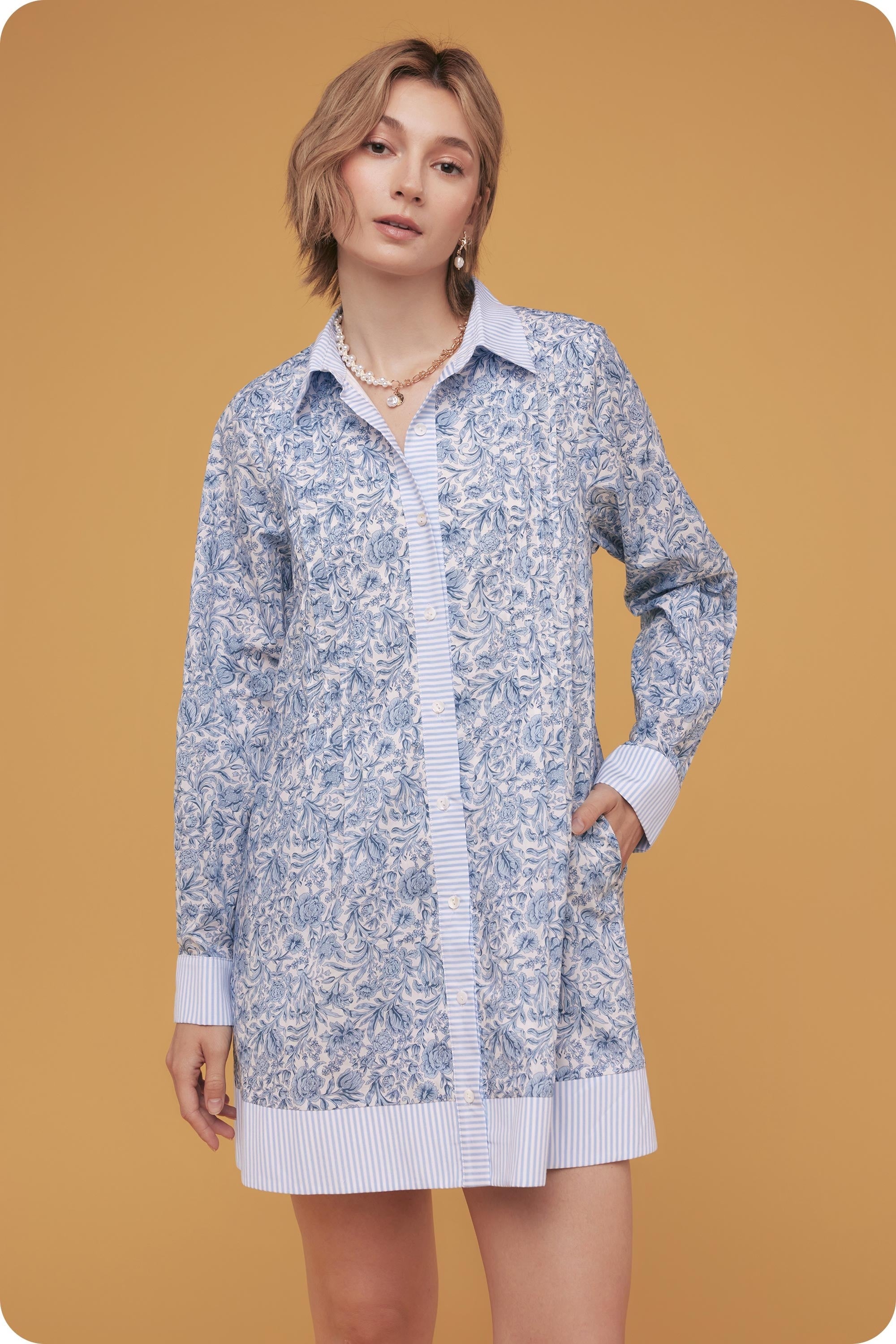 Woman wearing a floral cardigan over a striped shirt on a mustard yellow background