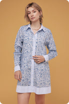 Woman wearing a blue floral dress against a mustard yellow background
