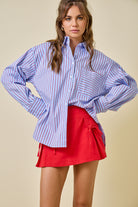 Woman wearing a blue and white striped shirt with a red skirt on a beige background