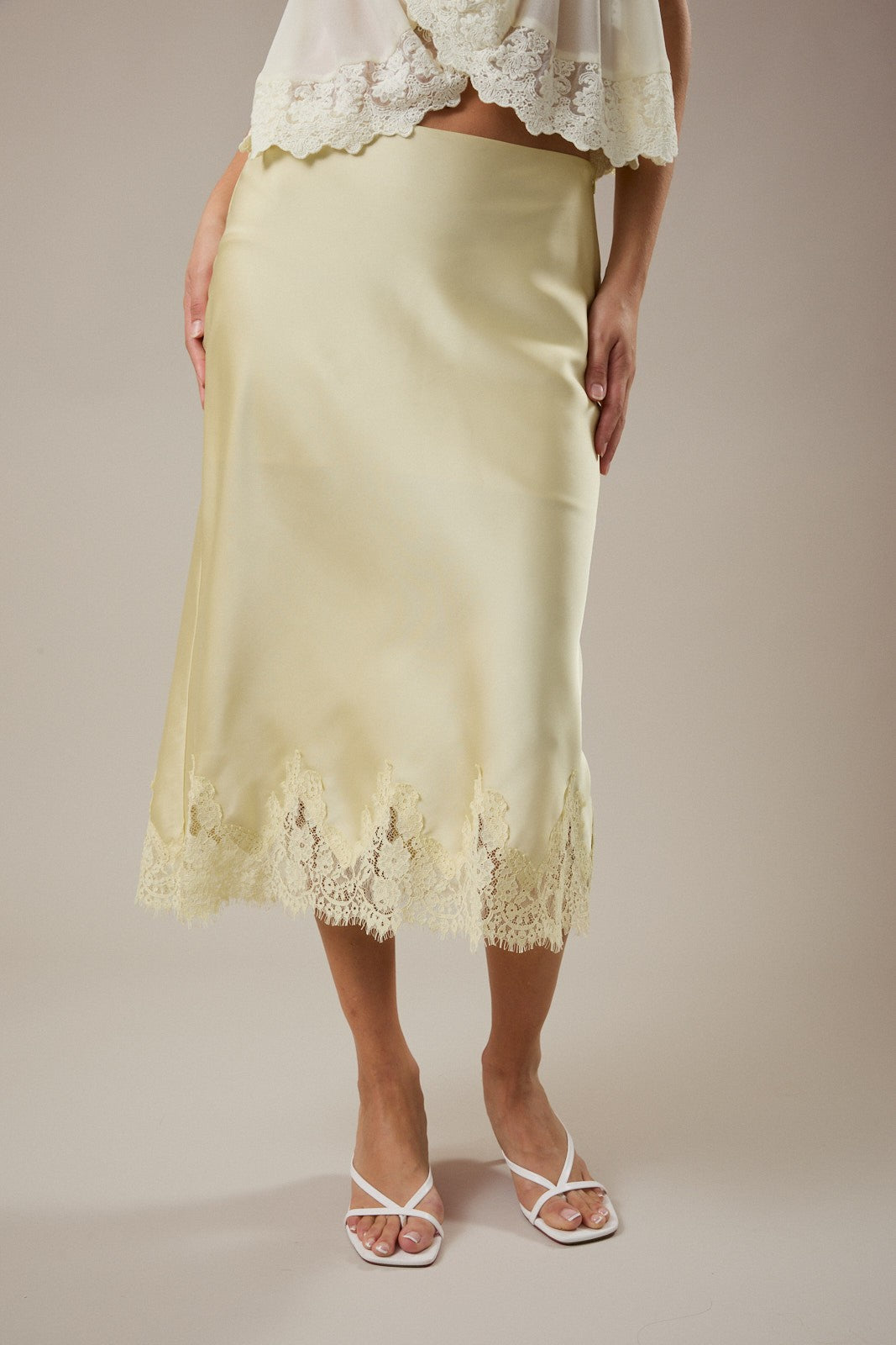 Light yellow skirt with lace trim worn by a person on a plain background