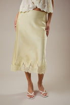 Light yellow skirt with lace trim worn by a person on a plain background