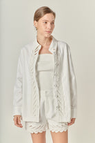 Woman wearing a white outfit with lace details on a plain background