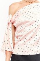 Pink polka dot one-shoulder top with a bow detail on a white background