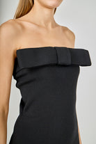 Black strapless dress with a bow detail on a neutral background