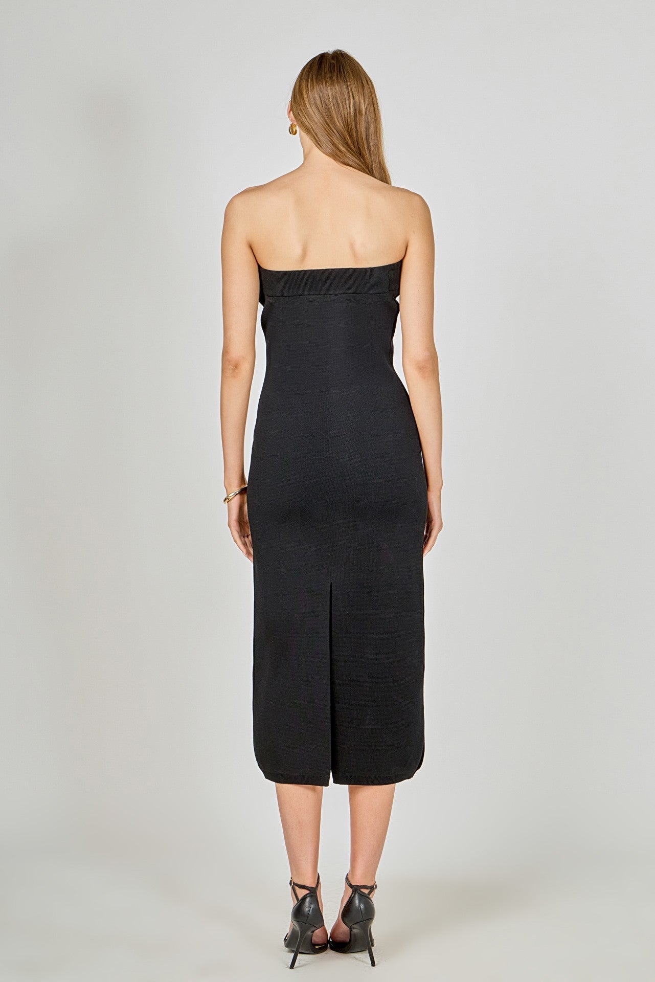 Woman wearing a black strapless dress on a plain background