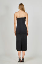 Woman wearing a black strapless dress on a plain background