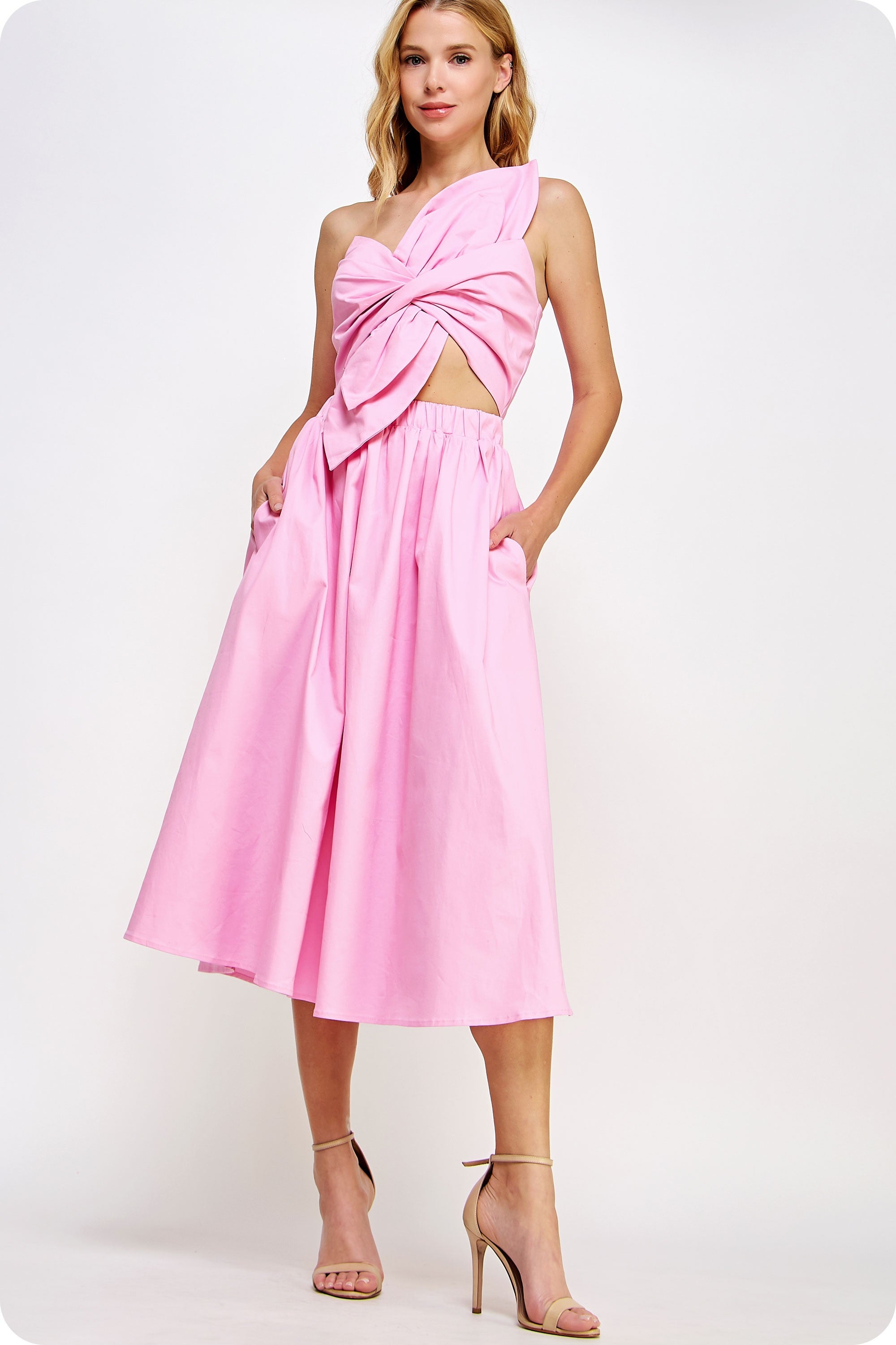 Woman wearing a pink dress with a cutout design on a white background
