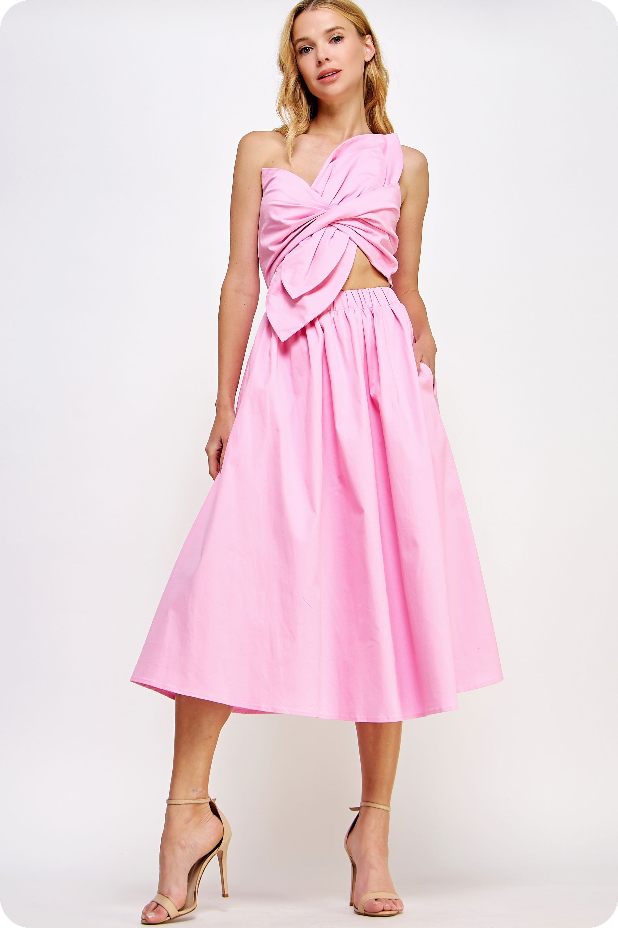 Woman wearing a pink dress with a cut-out design on a white background