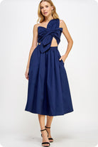 Woman wearing a navy blue dress with a bow detail on a white background