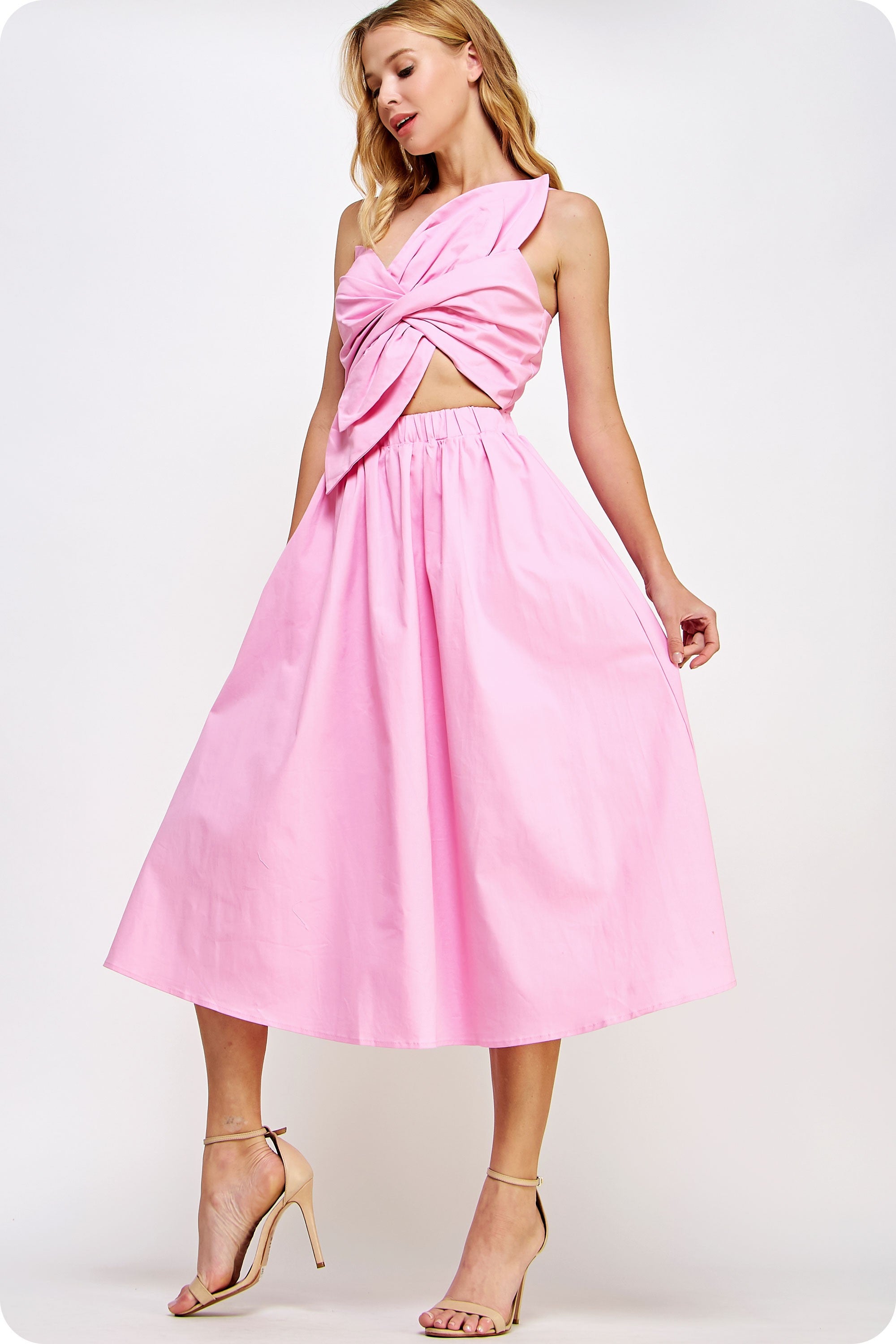 Woman wearing a pink dress with a cutout design on a white background