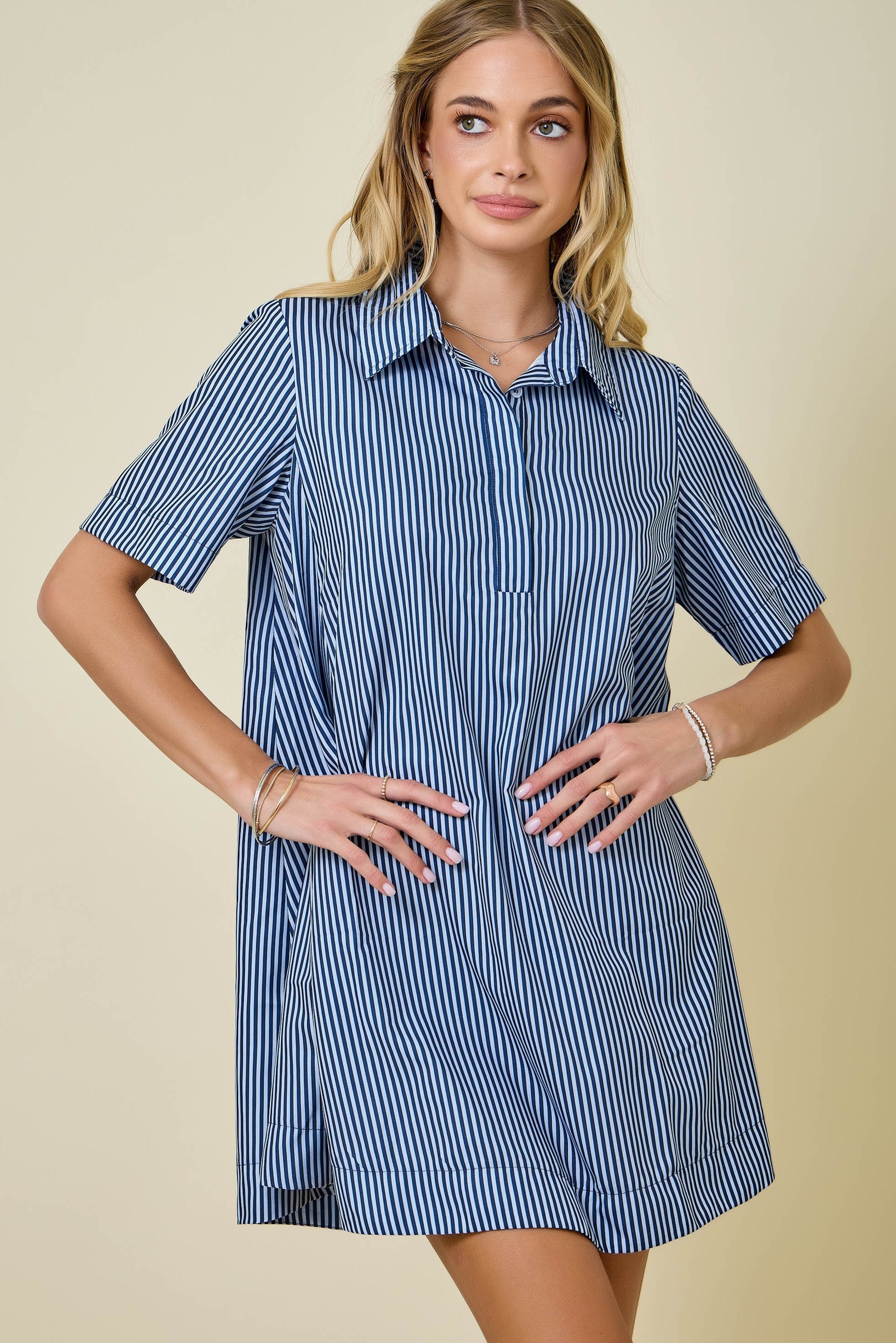 Woman wearing a blue and white striped dress against a beige background