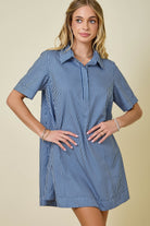 Woman wearing a blue and white striped dress against a beige background