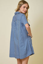 Woman wearing a blue and white striped shirt dress against a beige background