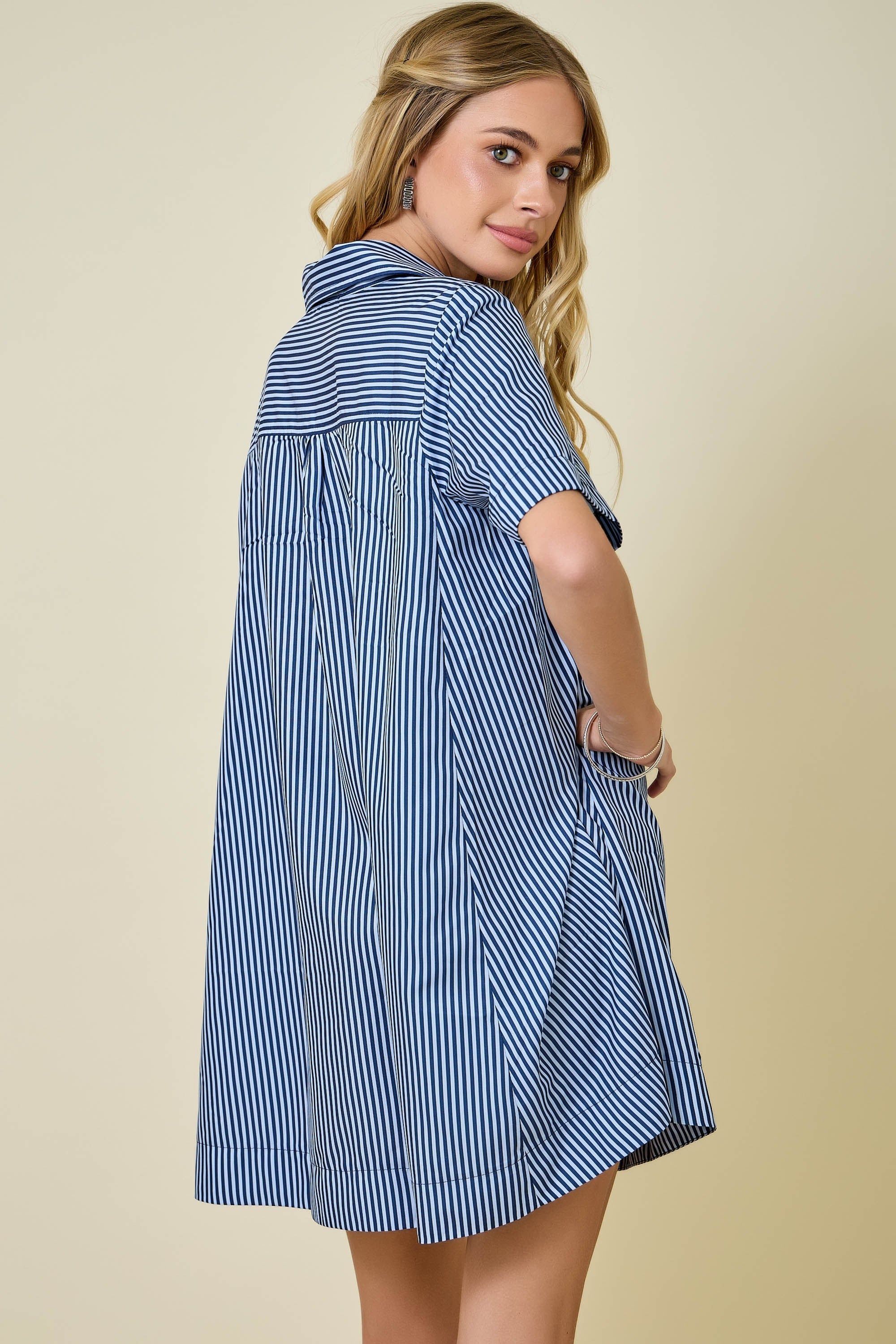 Woman wearing a blue and white striped shirt dress against a beige background