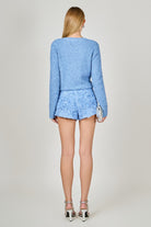 Woman wearing a blue textured outfit on a plain background