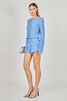 Woman wearing a blue outfit with a jacket and skirt on a light gray background