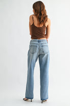 Woman wearing blue jeans and a brown top on a white background