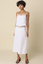Woman wearing a white dress with lace details on a beige background