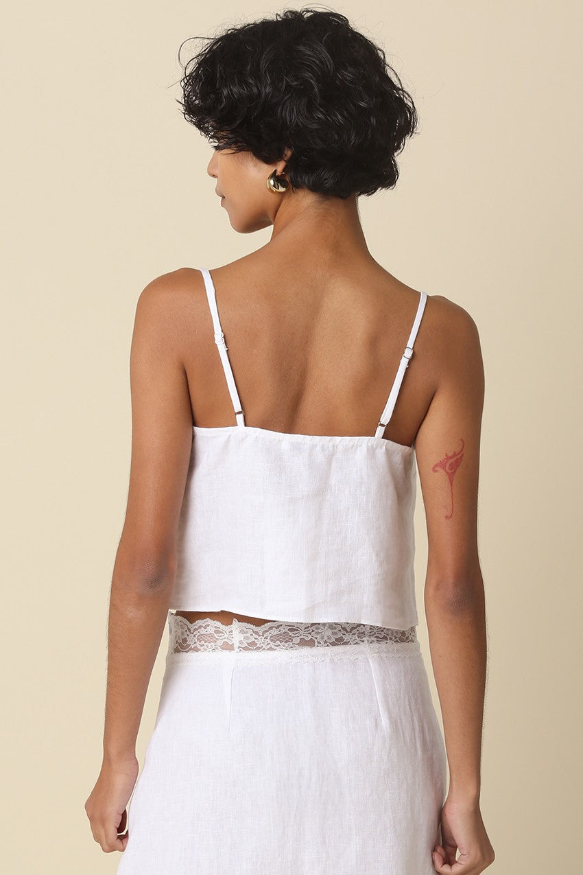 Woman wearing a white dress with thin straps on a beige background