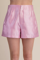 Pink shorts worn by a person on a beige background
