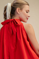 Woman wearing a red dress with a bow detail on a beige background