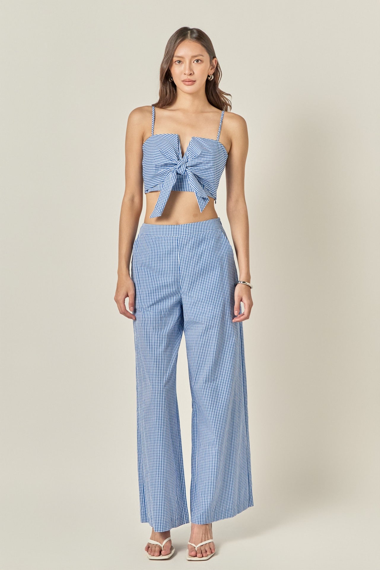 Woman wearing a blue top and checkered pants on a beige background