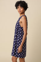 Woman wearing a navy dress with white polka dots on a beige background