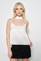 Woman wearing a white sleeveless top with buttons and a black skirt on a white background