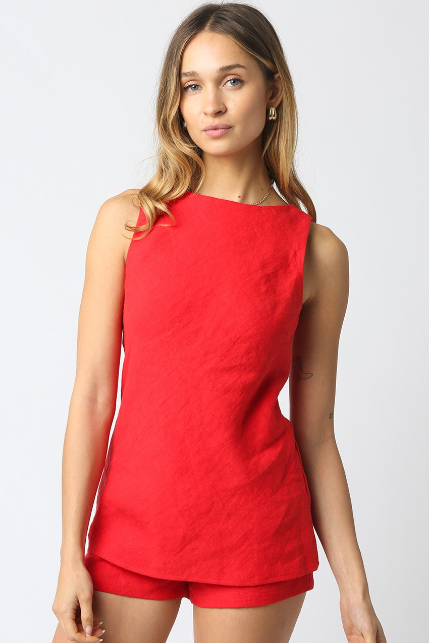 Woman wearing a red sleeveless top and shorts on a white background