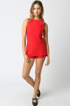 Woman wearing a red sleeveless top and shorts on a white background