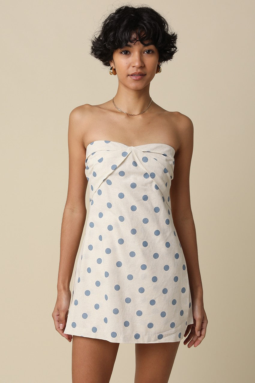 Woman wearing a strapless dress with blue polka dots on a beige background