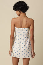 Woman wearing a strapless polka dot dress against a beige background
