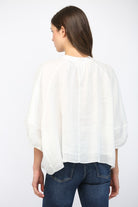 Person wearing a white blouse and blue jeans on a white background
