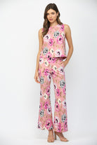Woman wearing a pink floral top and pants on a white background