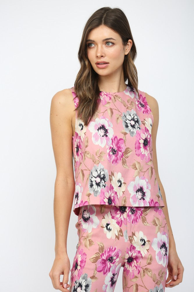 Woman wearing a pink floral sleeveless top and pants on a white background