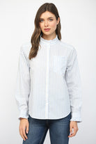 Woman wearing a white blouse with blue stripes and jeans on a white background