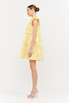 Woman wearing a yellow dress with floral patterns on a white background