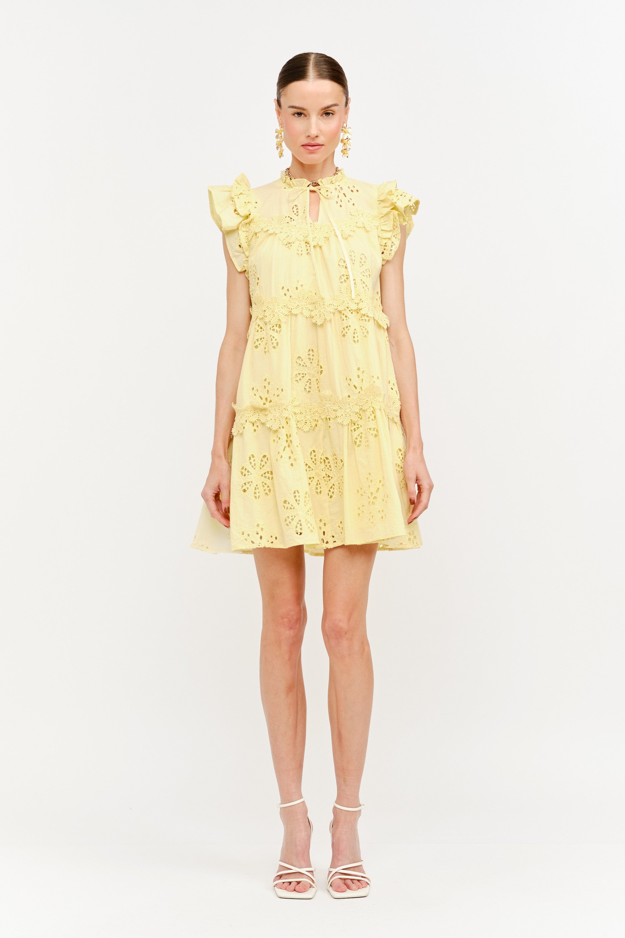 Woman wearing a yellow dress with floral embroidery on a white background