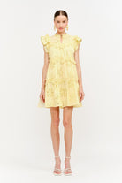 Woman wearing a yellow dress with floral embroidery on a white background