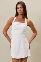 Woman wearing a white apron against a neutral background