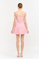 Back view of a person wearing a pink dress on a white background